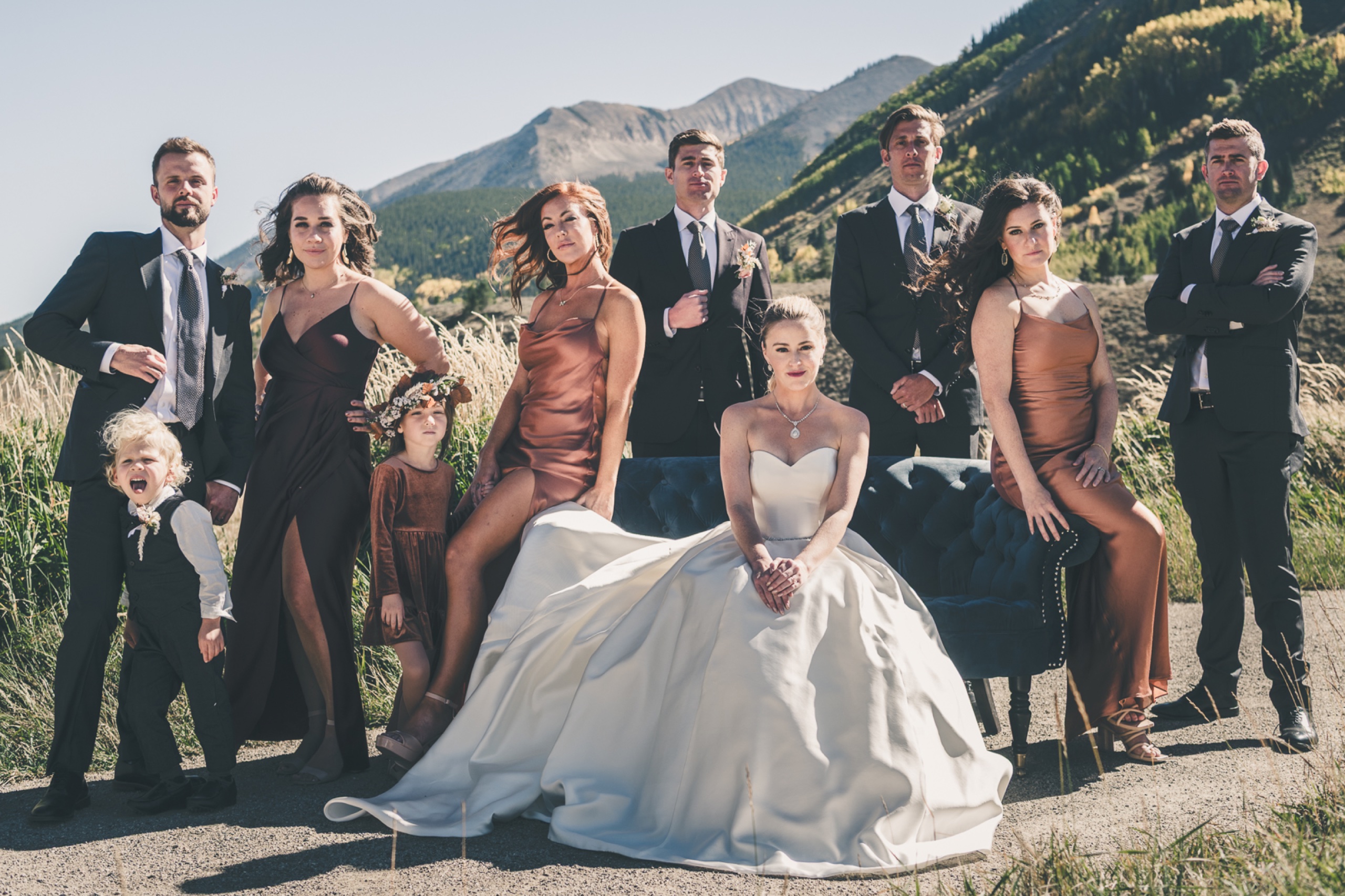 Editorial wedding party portrait with bride seated center and groomsmen and bridesmaids posed against Crested Butte mountains