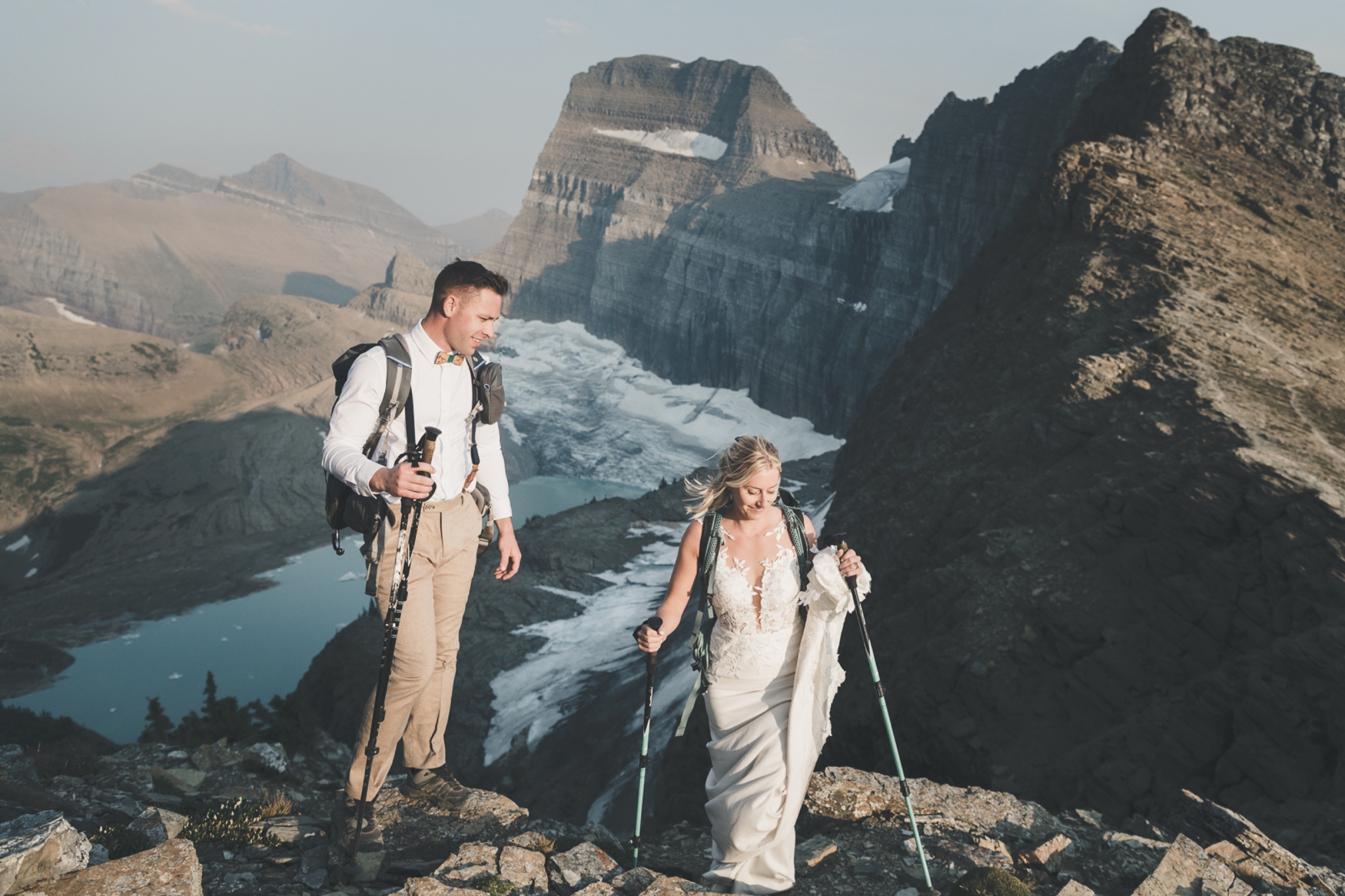 Bride and groom hiking in wedding attire above Grinnell Glacier in Glacier National Park, Montana