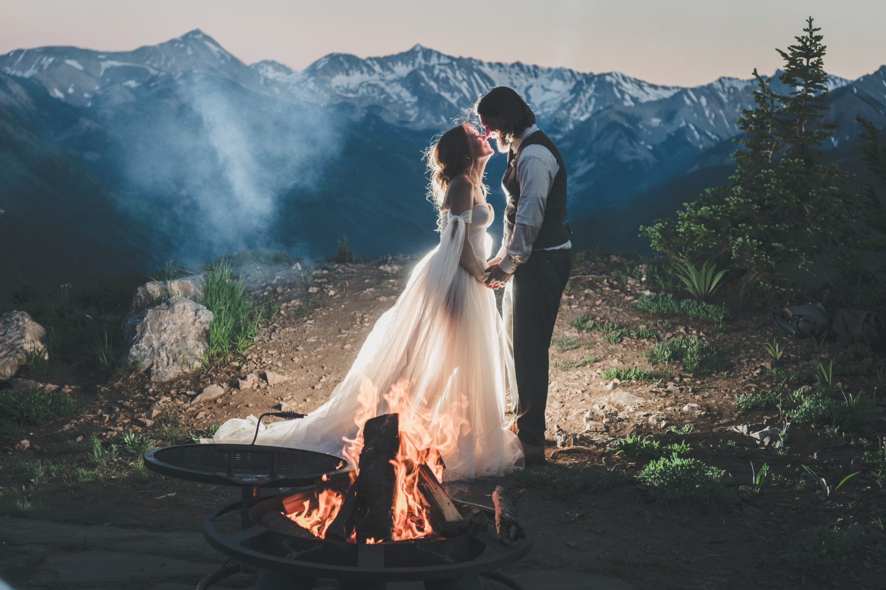 Elopement couple sharing an intimate moment by the campfire in the mountains